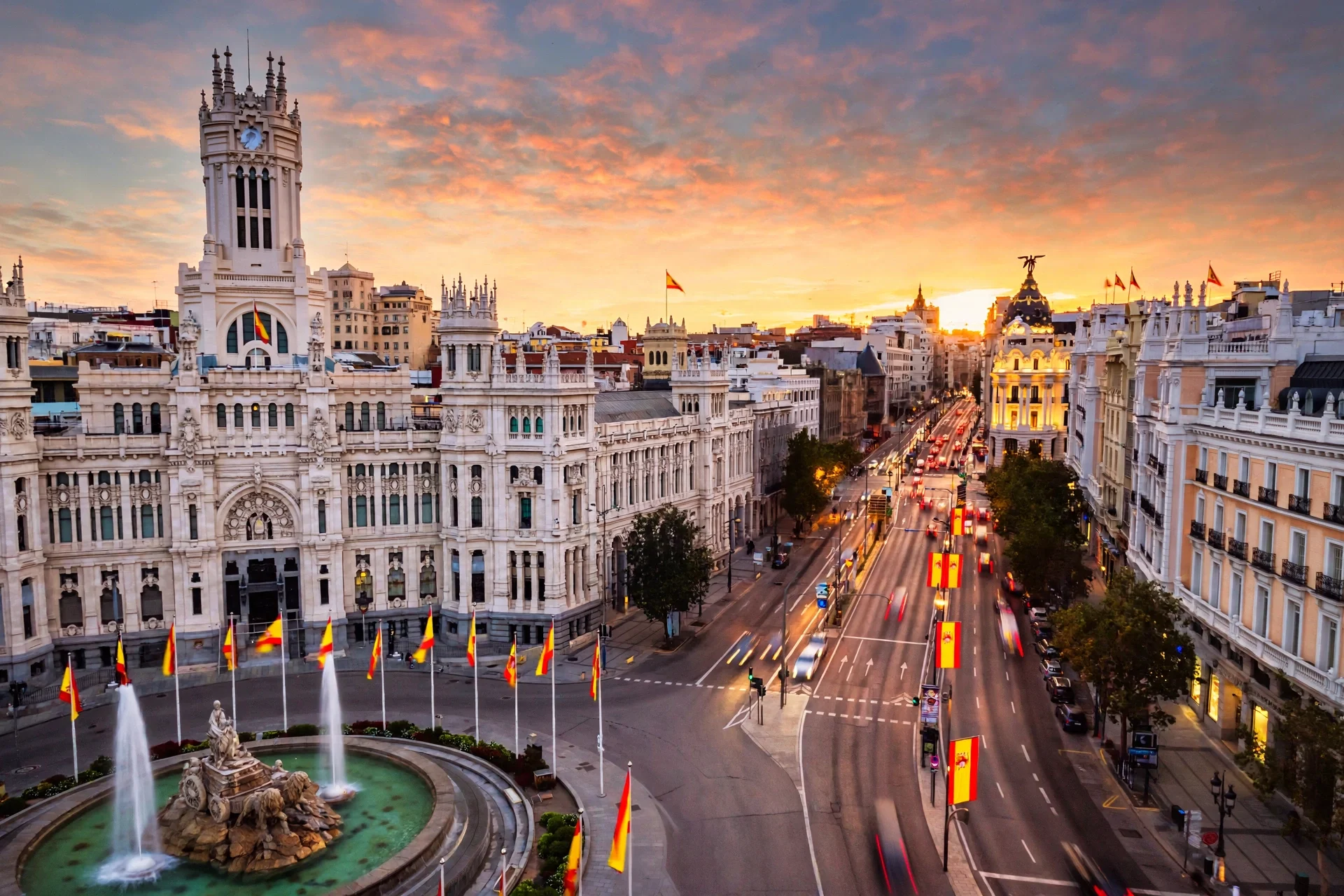 Palacio de Cibeles y Gran Vía de Madrid al atardecer con banderas de España
