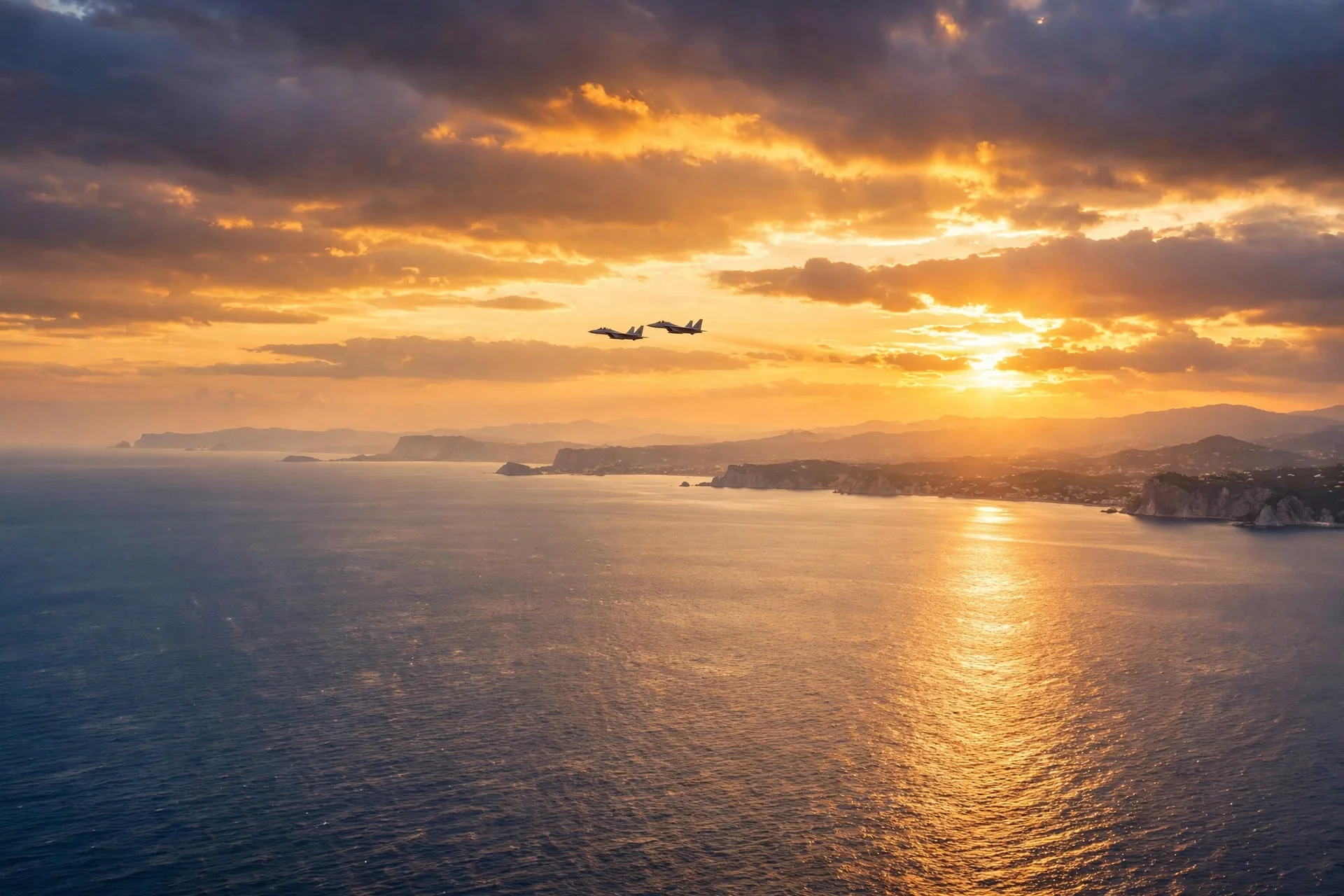 Dos cazas en formación sobre el Mediterráneo al atardecer, con la costa y el sol poniente al fondo