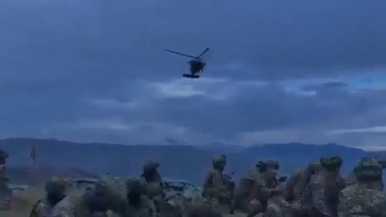 Helicóptero en vuelo sobre un grupo de militares en la zona del accidente en el Cauca al anochecer