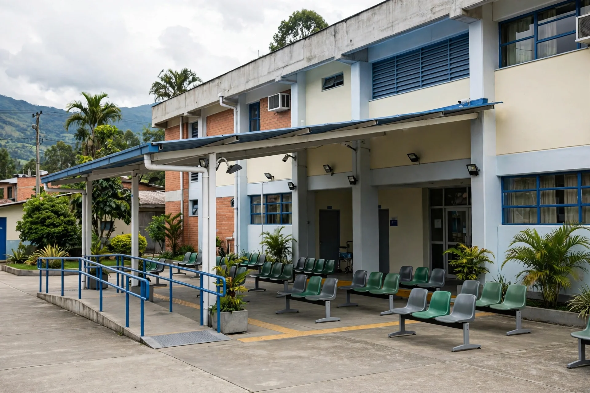 Exterior de un hospital público con sala de espera al aire libre y sillas vacías en una zona verde de Colombia