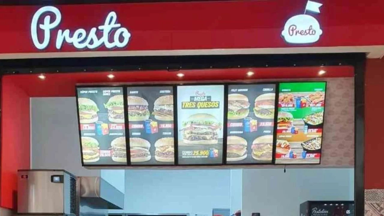 Interior de un restaurante Presto con el rótulo rojo de la marca y los tableros del menú de hamburguesas