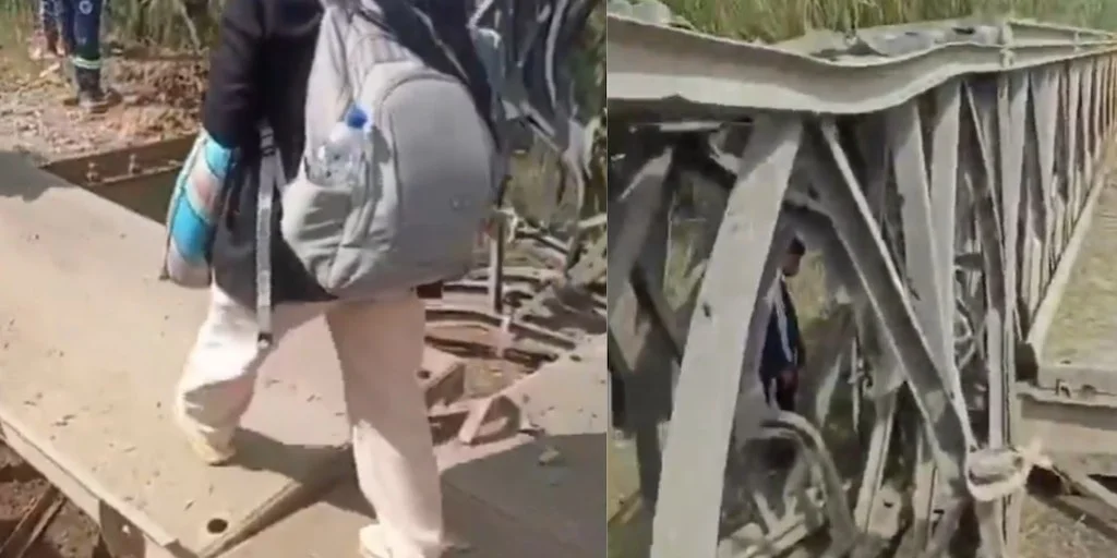 Una persona con mochila cruza la estructura metálica retorcida del puente afectado por las detonaciones en Santander de Quilichao, Cauca.