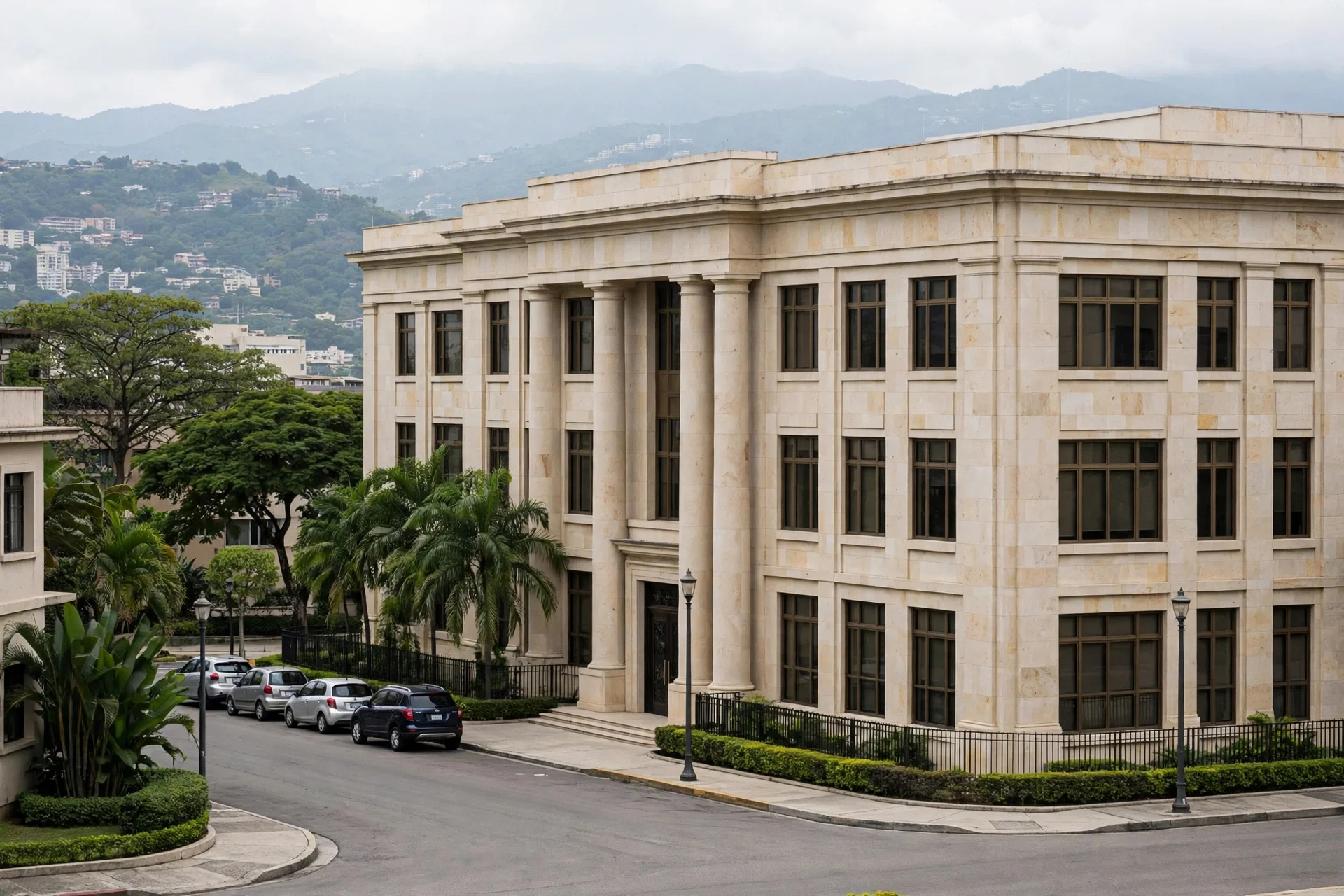 Edificio institucional sobrio de piedra clara con columnas en una calle tranquila de Caracas, con colinas verdes al fondo