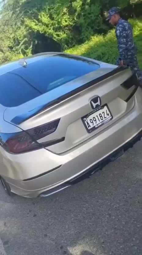 Vehículo detenido a un lado de la vía en Baní con un agente de policía junto a la parte trasera del carro